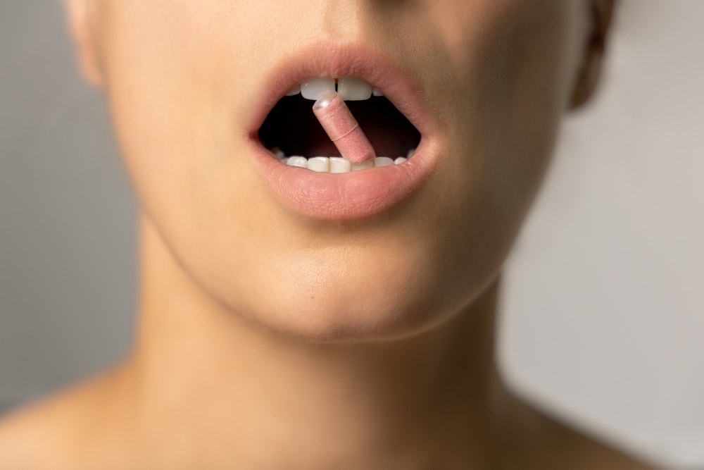 Oral health with supplements - mouth open, capsule between teeth