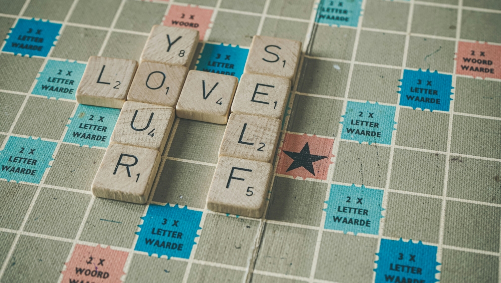 The words love yourself on a Scrabble board - overcoming past patterns